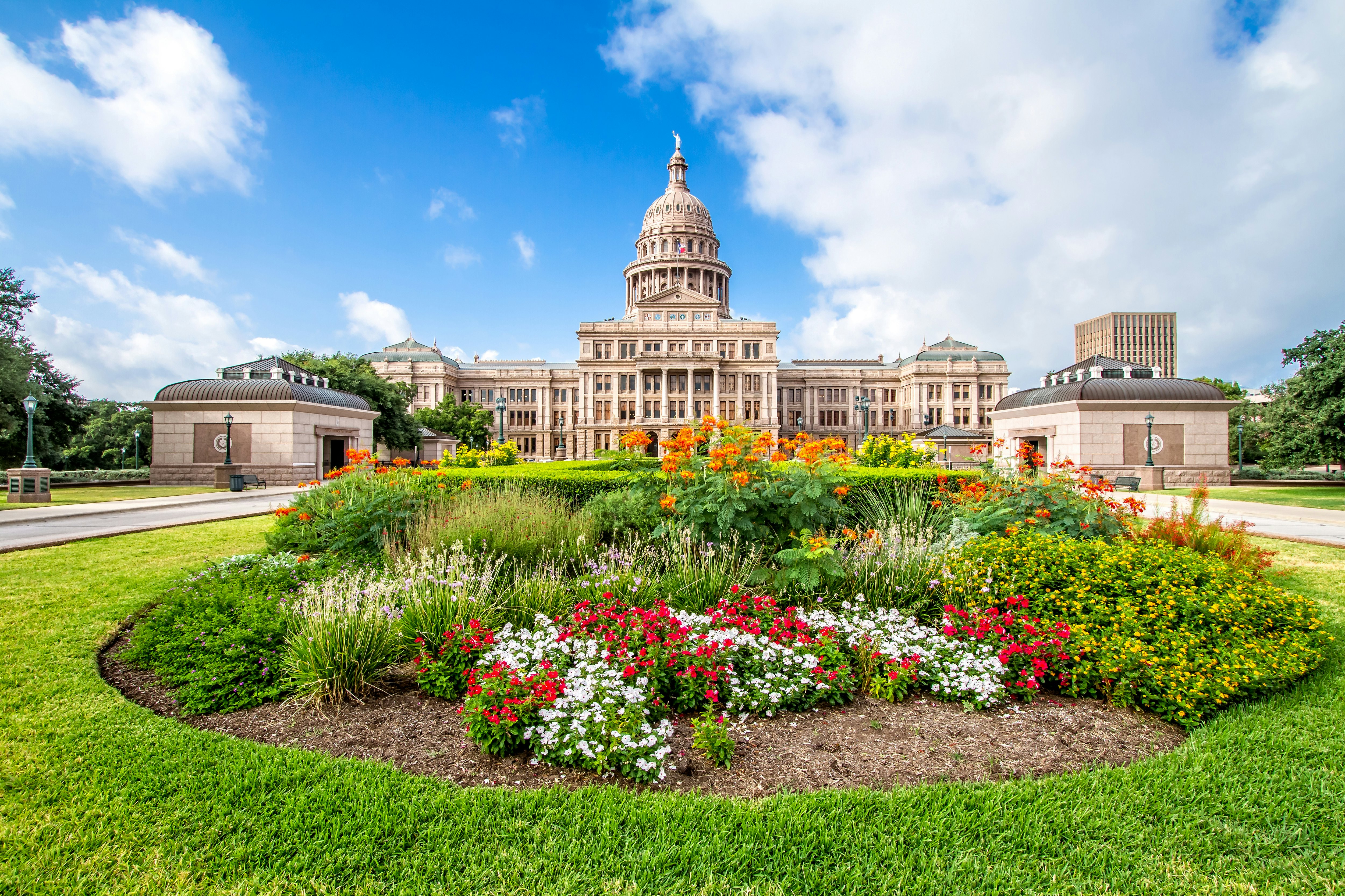 The Texas State Capitol with flower garden. It was completed in 1888 in Downtown Austin. It contains the offices and chambers of the Texas Legislature and the Office of the Governor.