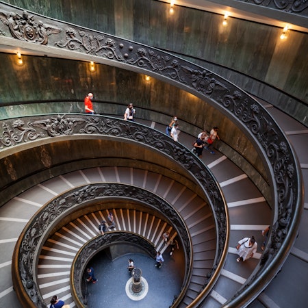 Tourists on a spiraling staircase in the Vatican Museums.