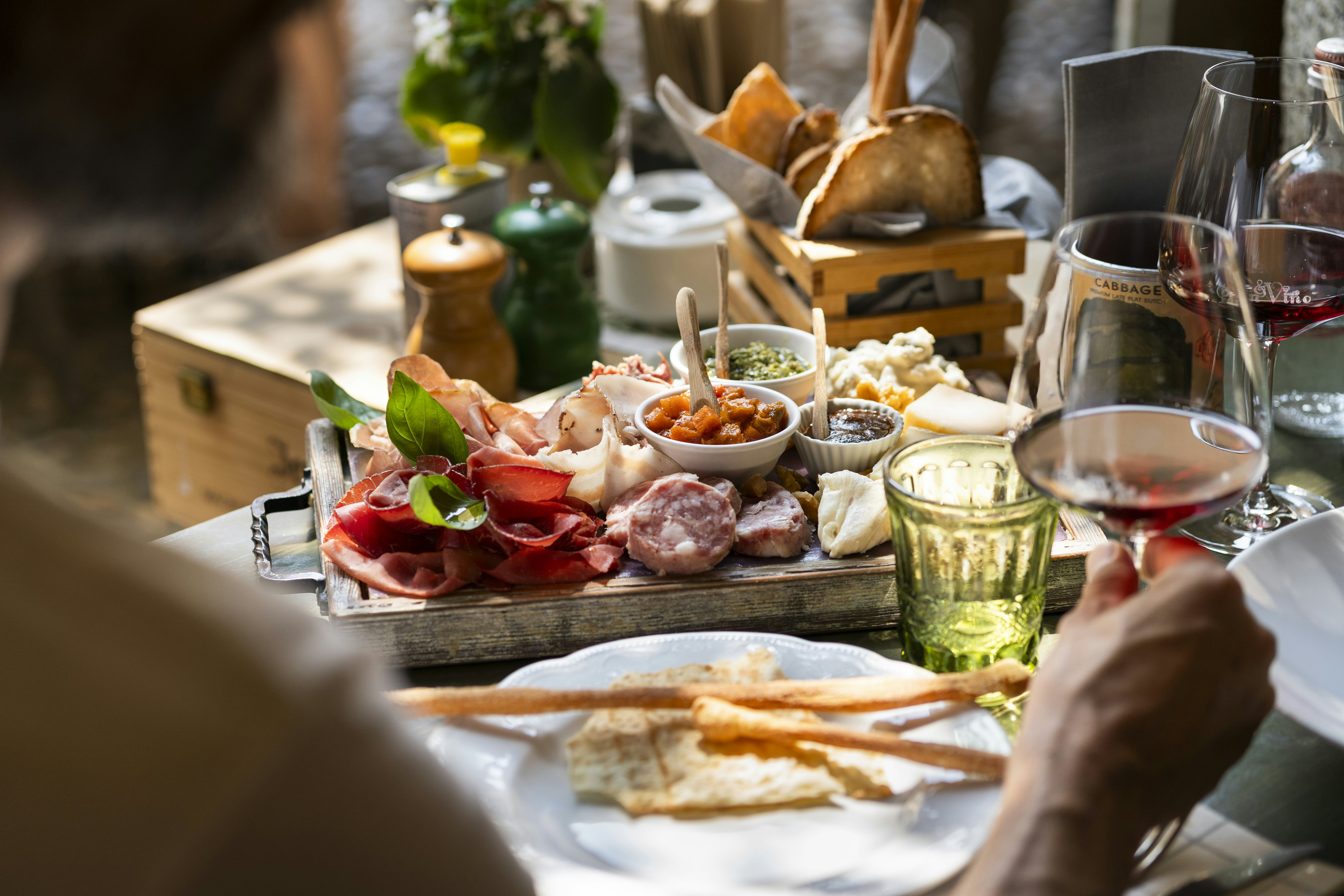 A platter of meats and cheeses served with water and red wine.