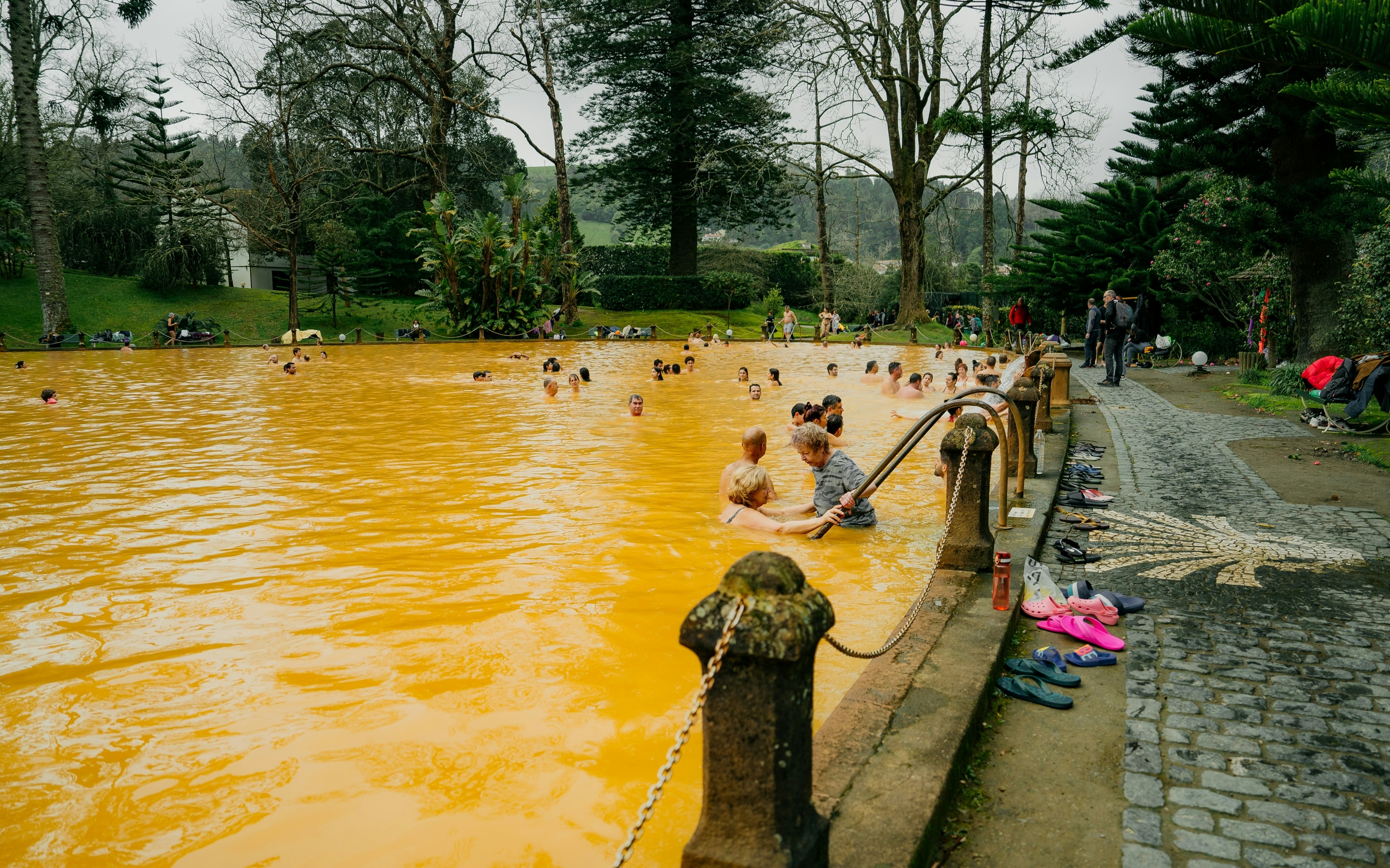 People swimming in a pool of yellow-colored thermal water.