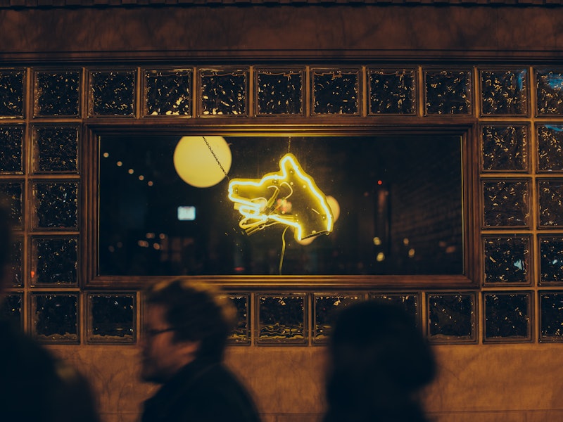 A window at night with a neon sign in the shape of a wolf.